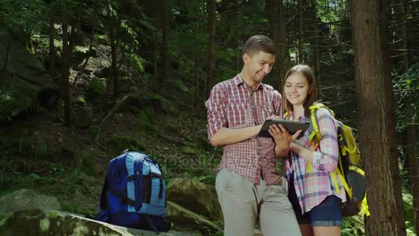 Un jeune couple de touristes avec des sacs à dos profiter d'une tablette sur un voyage. Navigation et recherche de direction — Video