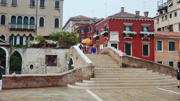 Venedig, Italien, juni 2017: Turister och ortsbor under parasoller går längs gatan i Venedig. dess regnar. Turism i Italien — Stockvideo