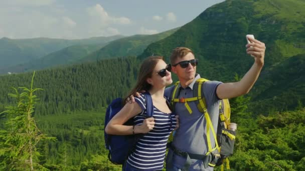 Bir kaç turist kendilerini, kameraya gülümseyen fotoğrafı. Bir dağ manzara arka planı — Stok video