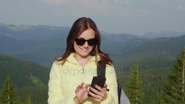 Bir smartphone Dağları'nın pitoresk bir zemin üzerinde genç kadının portresi ormanıyla kaplı. Her zaman online