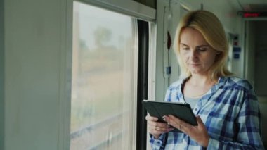 Genç bir gezgin bir tablet tren vagonuna kullanır. Pencerenin önünde duran