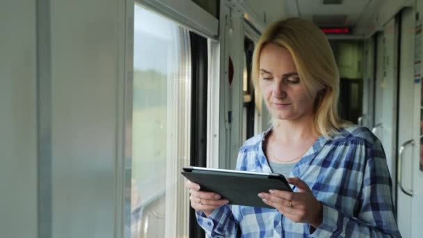 Portret van een jonge vrouw rijden van een trein, genieten van een tablet. Altijd in contact — Stockvideo