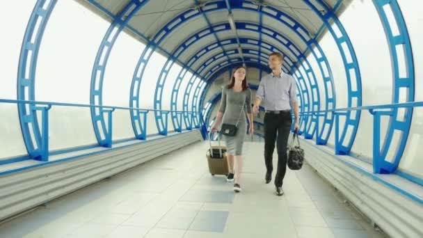 Ділові партнери - чоловік і жінка їдуть з багажем у терміналі вокзалу або аеропорту. Ділова поїздка, командна робота — стокове відео