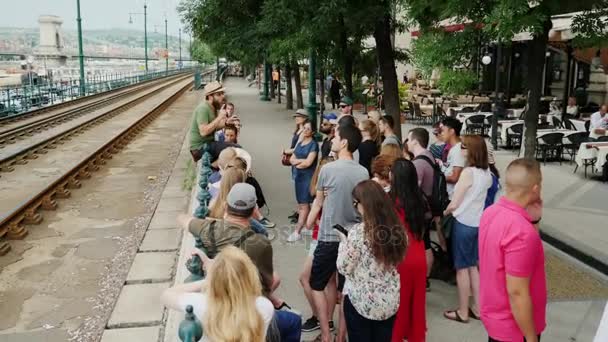 Boedapest, Hongarije, juni 2017: Vertelt de gids een groep toeristen over de stad van Budapest. Tegen de achtergrond van het stadsbeeld en de Kettingbrug — Stockvideo