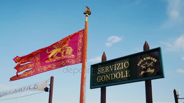 Venecia, Italia, junio de 2017: La bandera de Venecia y la placa del servicio de gondoleros. Sobre el fondo del cielo azul — Vídeos de Stock