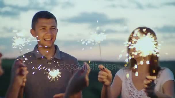 Amigos com fogos de artifício em suas mãos se divertindo em uma festa à noite. Vídeo em câmera lenta — Vídeo de Stock