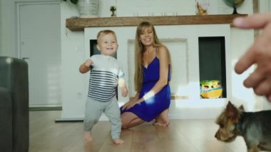 Neşeli küçük bir oğlan bebeği ilk adımlarını yapıyor. Baba, gülüyor annemden geliyor