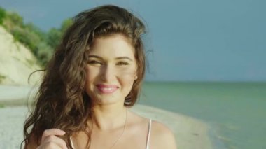 Tropikal bir plajda genç bir kadın portresi. Kameraya, görünüyor gülümseyerek. 4 k ağır çekim video