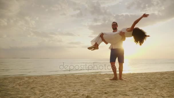 El marido rodea a su esposa en sus brazos. En el fondo del mar y la puesta del sol. Feliz luna de miel. — Vídeos de Stock