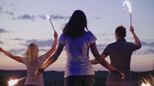 Группа друзей развлекается с фейерверками или бенгальскими огнями. Видео замедленного действия — стоковое видео