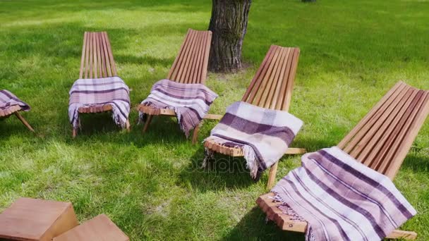 Декілька дерев'яних сонячних ліжок з килимами на зеленому газоні. Місце для відпочинку на курорті — стокове відео