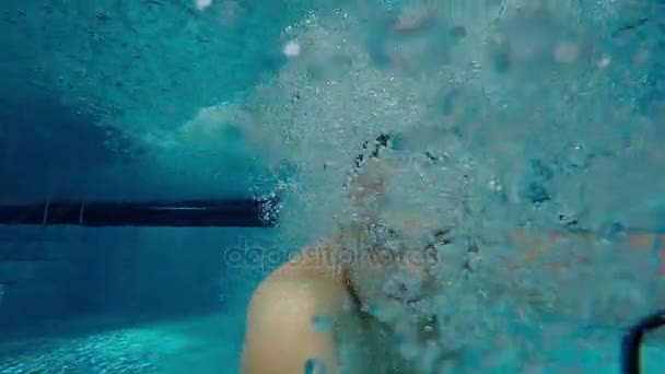 Un hombre nada bajo el agua en la piscina con los ojos abiertos, mirando a la cámara. Selfie submarino — Vídeos de Stock