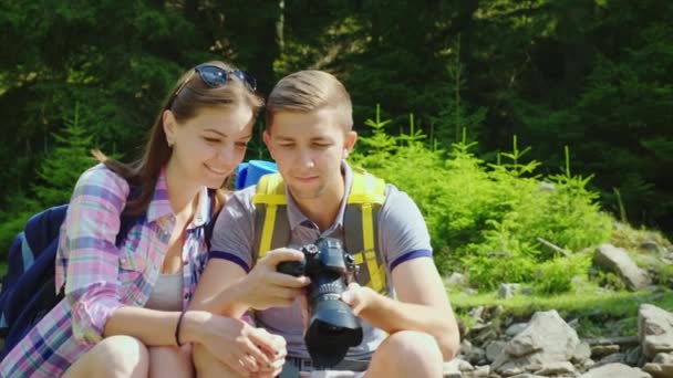 Ein glückliches Touristenpaar schaut durch die aufgenommenen Fotos in die Kamera. toller Urlaub und gute Erinnerungen — Stockvideo