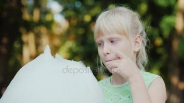 Tatlı Pamuk yün parkta yeme bir sarışın kız portresi. Bir açık yaz günü, bir mutlu tatil