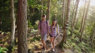 Genç bir çift turist ayar güneş ışınlarının bir dağ yolunda yürüyorduk. Steadicam yavaş hareket atış