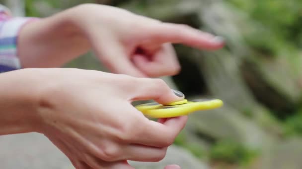 As mãos femininas brincam com um brinquedo giratório. Vídeo com profundidade de campo rasa — Vídeo de Stock