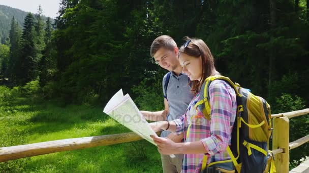 Turism och aktiv livsstil. Ett ungt par ser på kartan, stå i en pittoresk plats på en klar dag sommar — Stockvideo