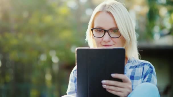 Retrato de uma jovem mulher desfrutando de um tablet no pátio de sua casa. Conceito - tecnologia e ensino à distância — Vídeo de Stock