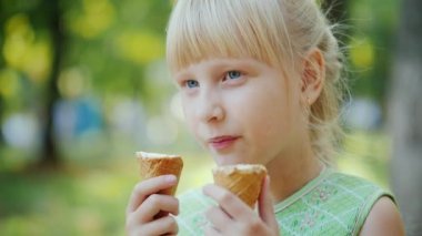 6 yaşındaki kız aynı anda iki külah lezzetli dondurma yedim. Yaz tatili, parkta dinlenme