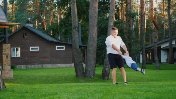 Ein gesunder Vater spielt mit seinem kleinen Sohn im Hof seines Hauses — Stockvideo