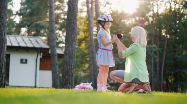Mutlu zaman birlikte. Anne kızına koruyucu eldiven üzerine koyar, onlar üzerinde paten kaymayı hazırlamak