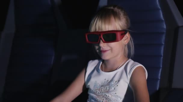 Chica rubia cool en gafas 3D viendo una película en el cine. Sopla el viento, la silla dinámica en movimiento — Vídeo de stock