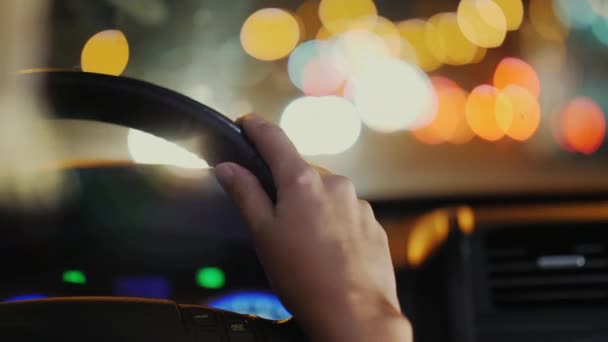 Conducir por la noche en la ciudad. Manos femeninas en el volante, vídeo con una profundidad de campo poco profunda — Vídeo de stock