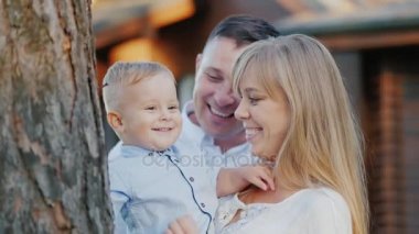 Genç, mutlu bir aile portresi. Anne, baba ve bebek çocuk parkta yürüyüş