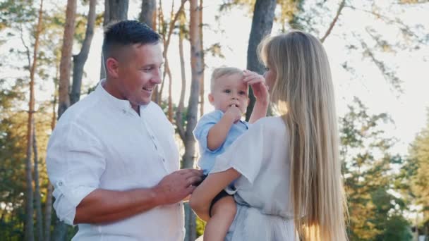 Portrait d'une jeune famille heureuse. Maman, papa et bébé garçon marchant dans le parc — Video