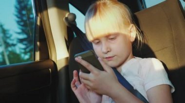 Kız bir smartphone üzerinde oynarken bir arabada seyahat. Yolda bir çocuk ile