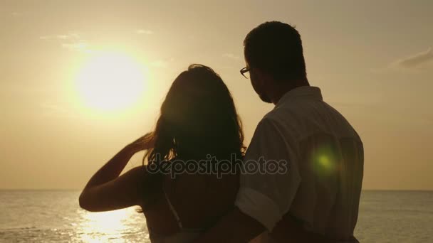Молодая пара любуется закатом над морем. Вид сзади — стоковое видео