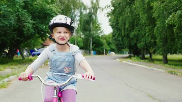 Rolig blond tjej rider en cykel på gatan. Ler, tycker resan. Steadicam skott — Stockvideo