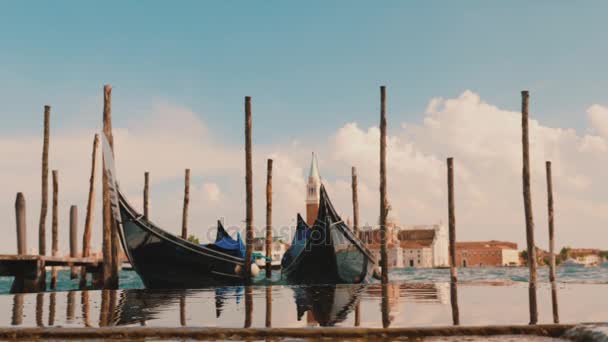 Gondolák van kikötve, a parton, fa cölöpök a mólón. A szimbólum a Velence és a turizmus, Olaszország — Stock videók