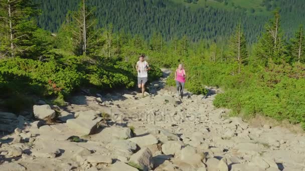 Prueba de resistencia y carrera extrema. Un hombre y una mujer corren por el sendero de la montaña — Vídeos de Stock