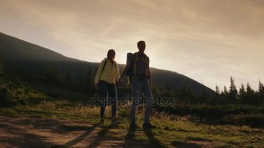 Genç çift elele, turist ayar güneş ışınlarının bir dağ yolunda yürüyorduk