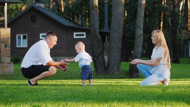 Bebeği öper babası. Mutlu genç aile ile 1 yaşındaki oğulları bahçede oynarken — Stok video