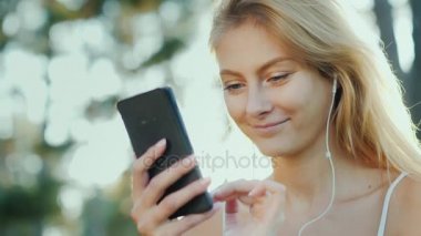 Şık bayanlar bir akıllı telefon kullanın. Tatile, güneş ışınlarının güzel saçlarını aydınlatmak