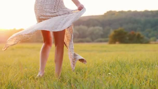 Giovane donna in una torsione abito leggero, la gonna lampeggia di fronte al sole al tramonto — Video Stock