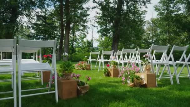 Pelouse verte avec rangées de chaises blanches en bois. Place pour la cérémonie de mariage. Steadicam shot 