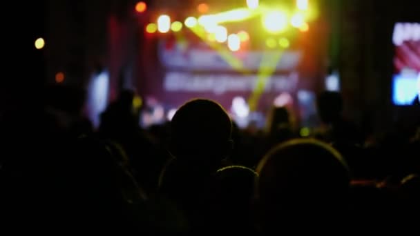 Натовп невпізнаваних глядачів на вуличному рок-концерті. Вид ззаду, силуети — стокове відео