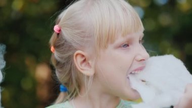 Kız lezzetli tatlı Pamuk yün parkta yiyor. Yan görünüm