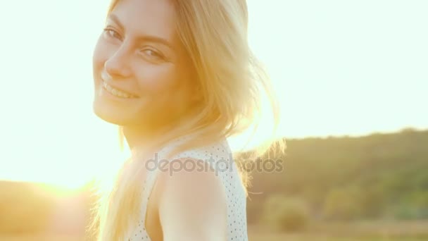 Портрет милой молодой женщины на закате. Оранжевый свет подчеркивает ее волосы сзади. Видео замедленного действия — стоковое видео