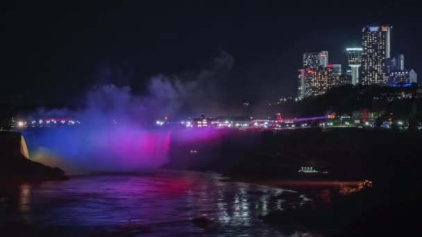 Niagara fällt in der Nacht. im Rahmen sieht man die amerikanische und kanadische Küste, der Wasserfall wird von Flutlichtern beleuchtet — Stockvideo