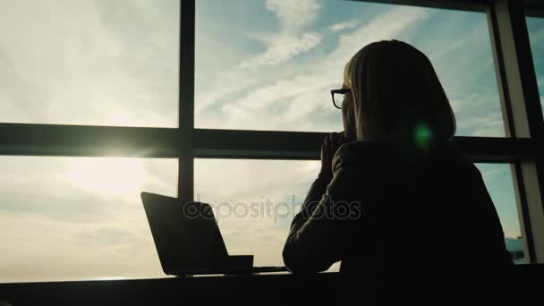 Una mujer con traje de negocios mira por la ventana de su oficina. Concepto - mirar hacia el futuro en los negocios — Vídeos de Stock