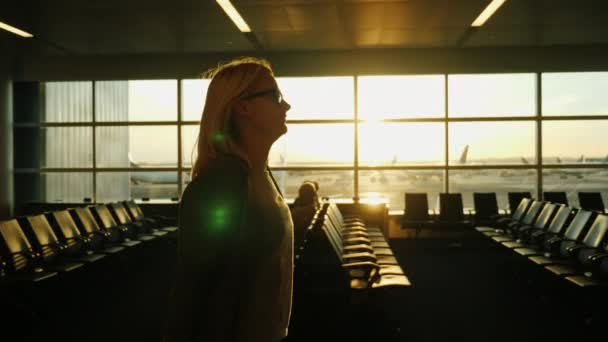 Joven mujer de negocios que va por la terminal del aeropuerto. Al atardecer. Steadicam tiro — Vídeo de stock