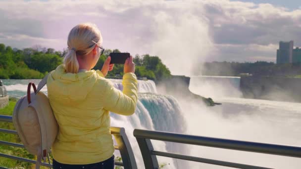 Een vrouw toeristische neemt foto's van de beroemde Niagara Falls in de VS — Stockvideo