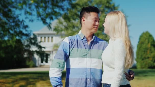 Glückliches junges Paar vor dem Hintergrund ihrer amerikanischen Heimat. Chinesischer Mann und kaukasische Frau — Stockvideo