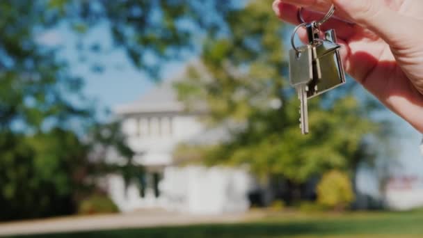 小さな家とキーの形をしたキーチェーンと手。米国の郊外様式の典型的な家の背景 — ストック動画