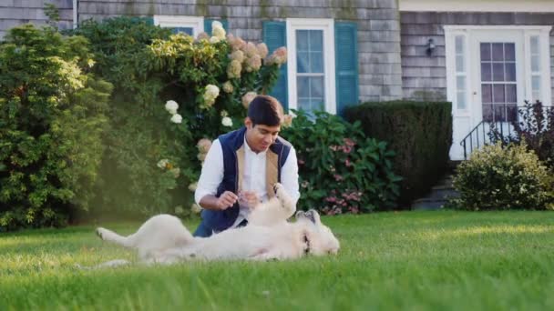 Un jeune Indien joue avec un chien dans son jardin. Animaux préférés — Video