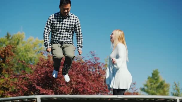 En man och en kvinna ha kul, hoppa på en studsmatta. Lycklig tid tillsammans. Slow motion 180 fps video — Stockvideo